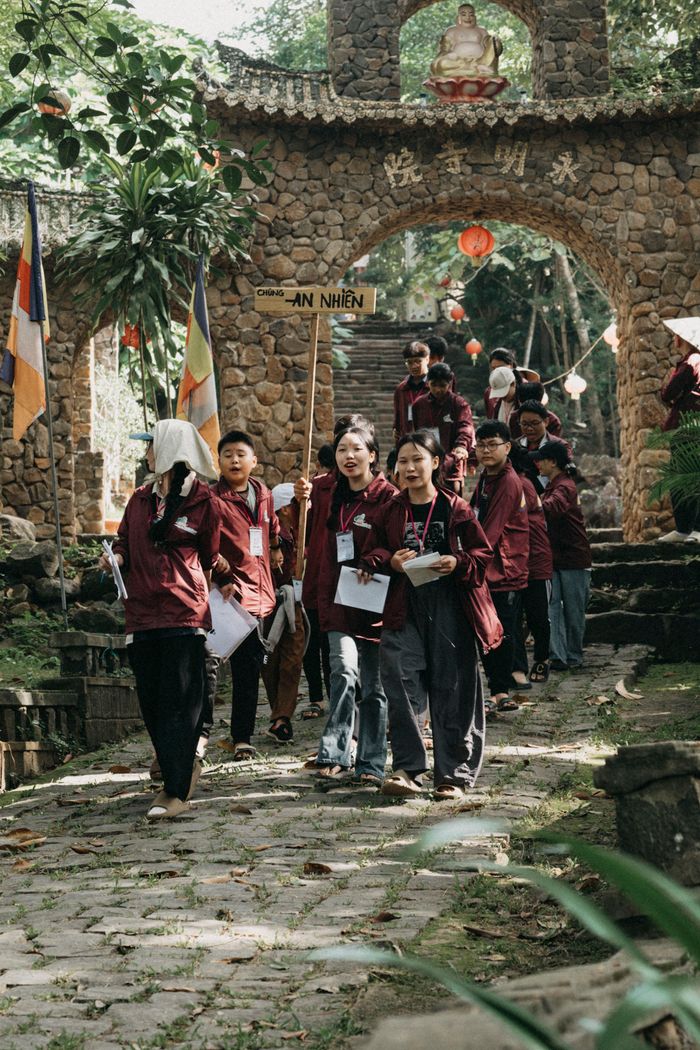 A group of teenagers with notepads exploring a garden with a traditional stone gateway.