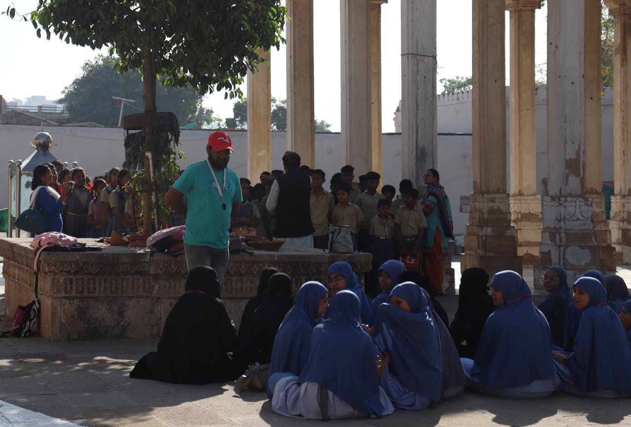 Students in uniforms visiting a historical site with columns and shadows. Education and culture.