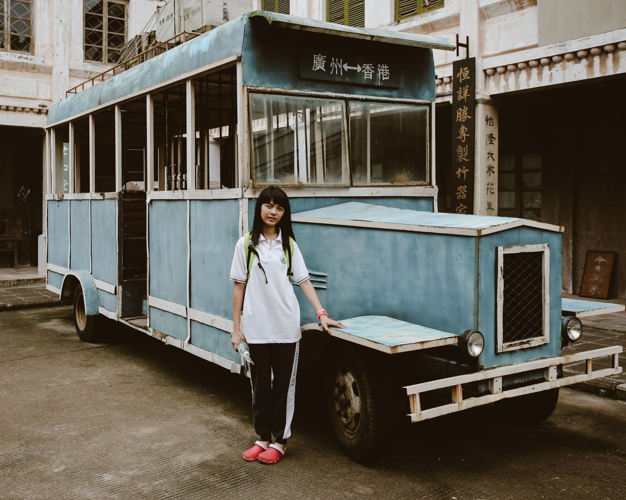 Teen girl poses with vintage bus exhibit at a museum, showcasing historical transport.